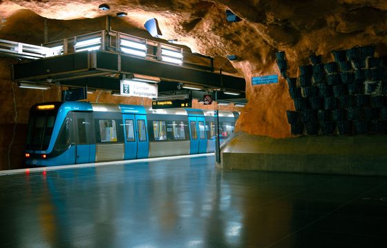 A metro train at a Stockholm platform cut from bare blue-painted rock
