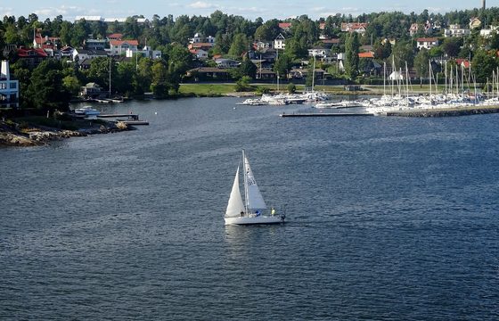 A sailing boat between wooded islands in the Stockholm archipelago