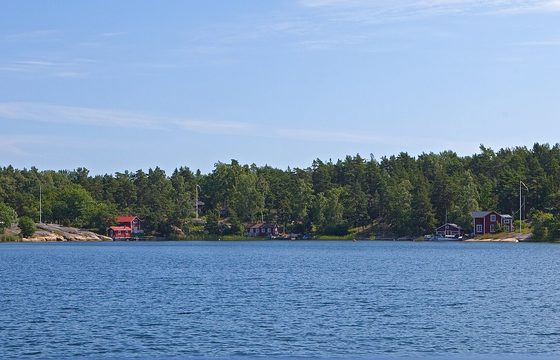 A wooded archipelago island with a red cabin at the shoreline