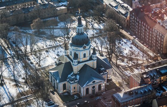 A snow-covered Stockholm church and rooftops in flat winter light
