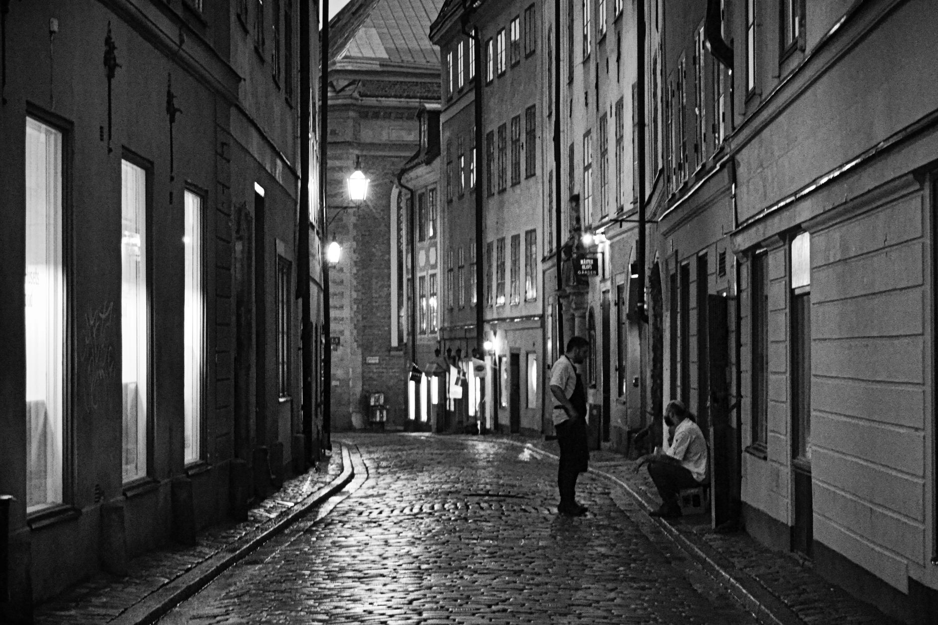 Cobblestone street in Norrmalm, Stockholm at night with streetlights and people. — illustrating How Does Paying Work in Stockholm, and Is Cash Still Used?