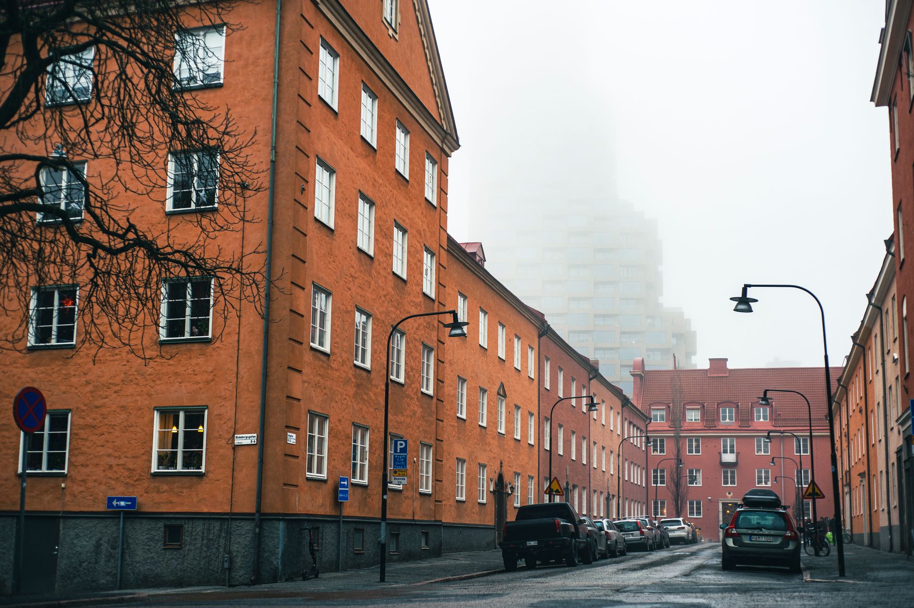 A foggy day on a residential street in Stockholm with parked cars and classic architecture. — illustrating How Much Swedish Do You Need in Stockholm?