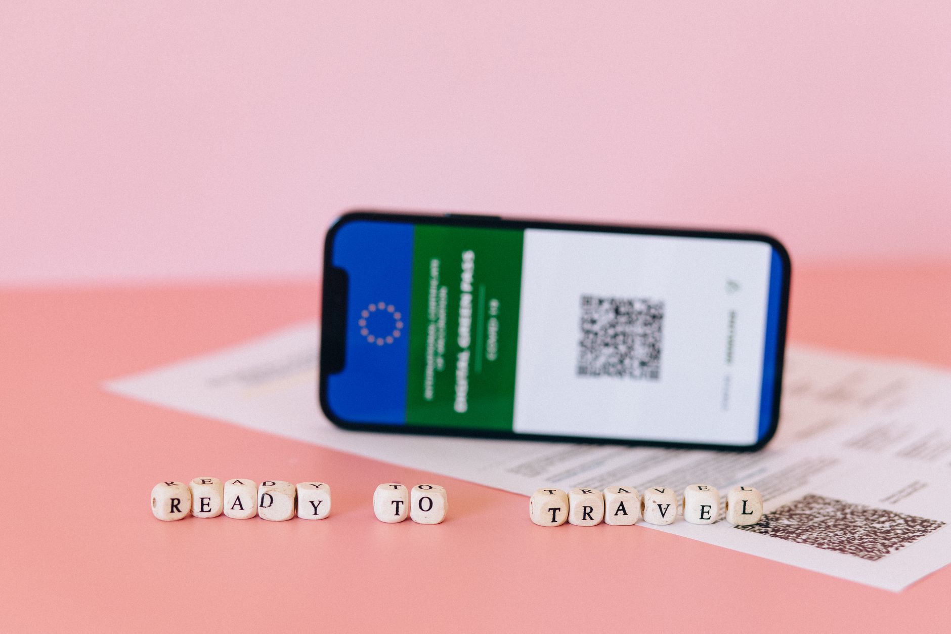 Smartphone displaying digital green pass on a pink surface with travel beads. — illustrating What Is the Stockholm Pass, and What Does It Cover?