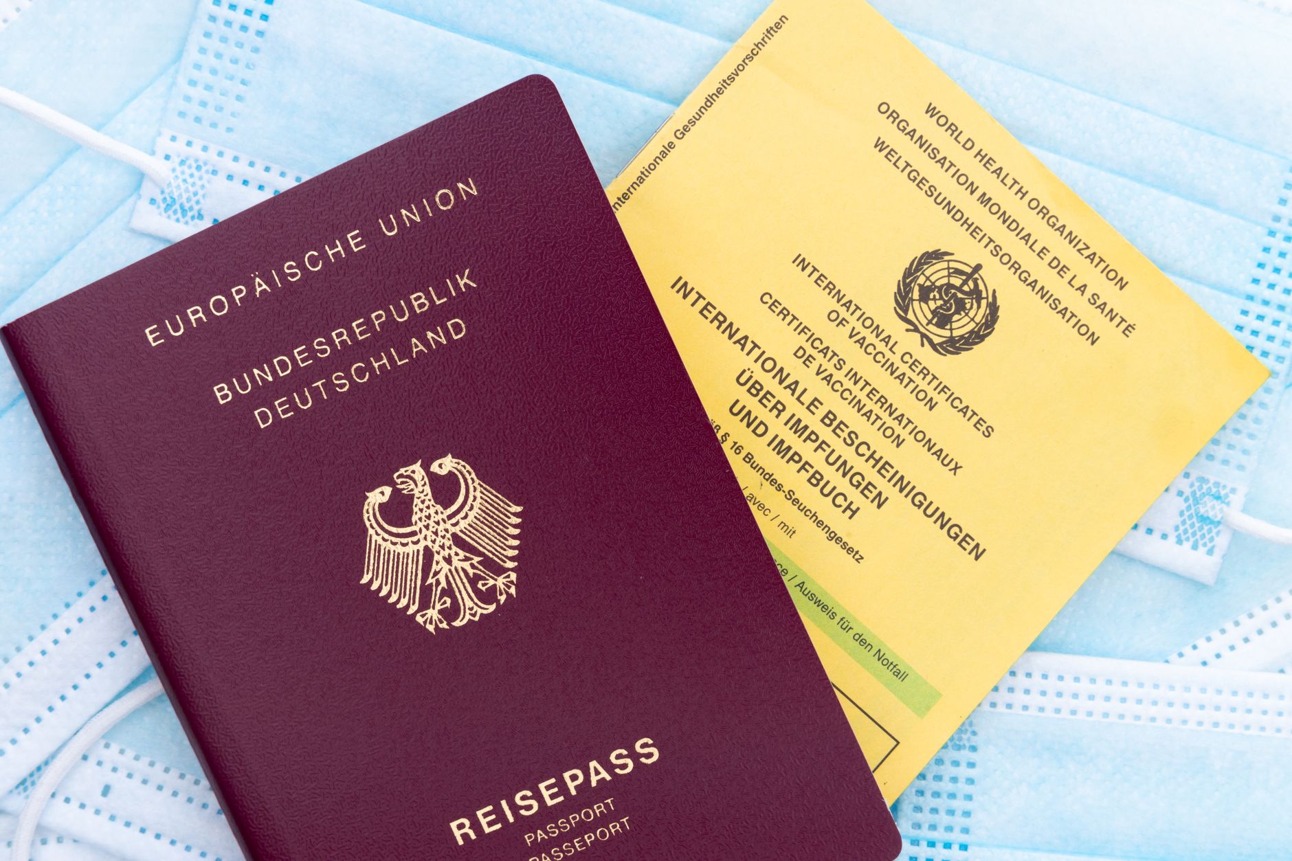 German passport, vaccination card on masks symbolizing travel and health