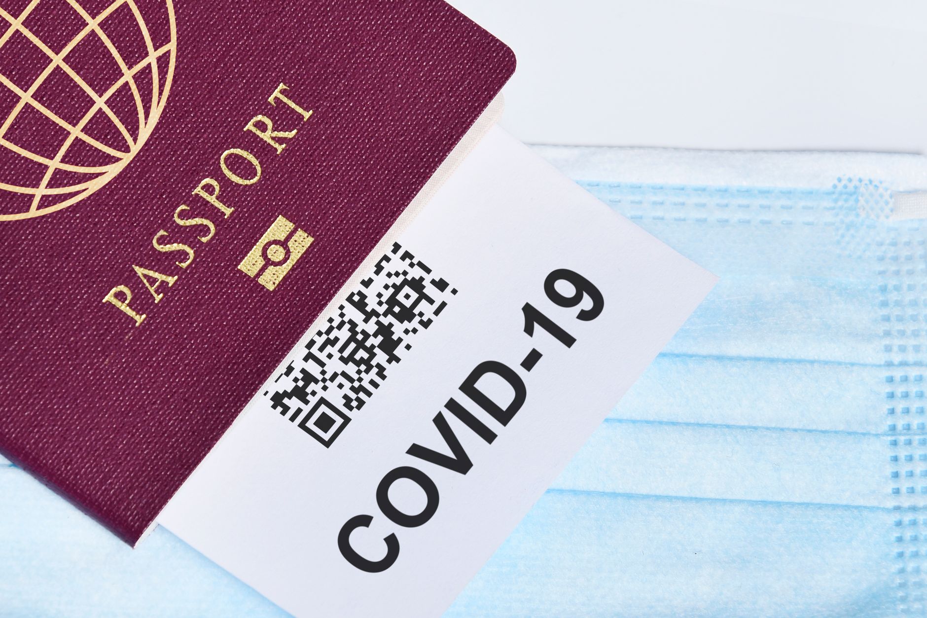 Close-up of a passport with a COVID-19 QR code and surgical mask, representing travel during the pandemic