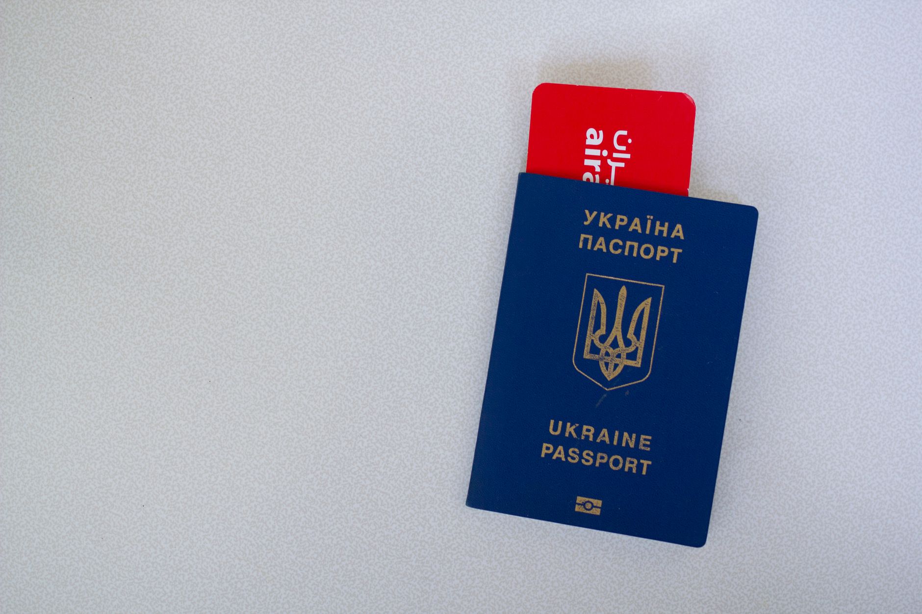 Close-up of a Ukrainian passport with an airline boarding pass on a white surface. — illustrating What Is the Stockholm Pass, and What Does It Cover?