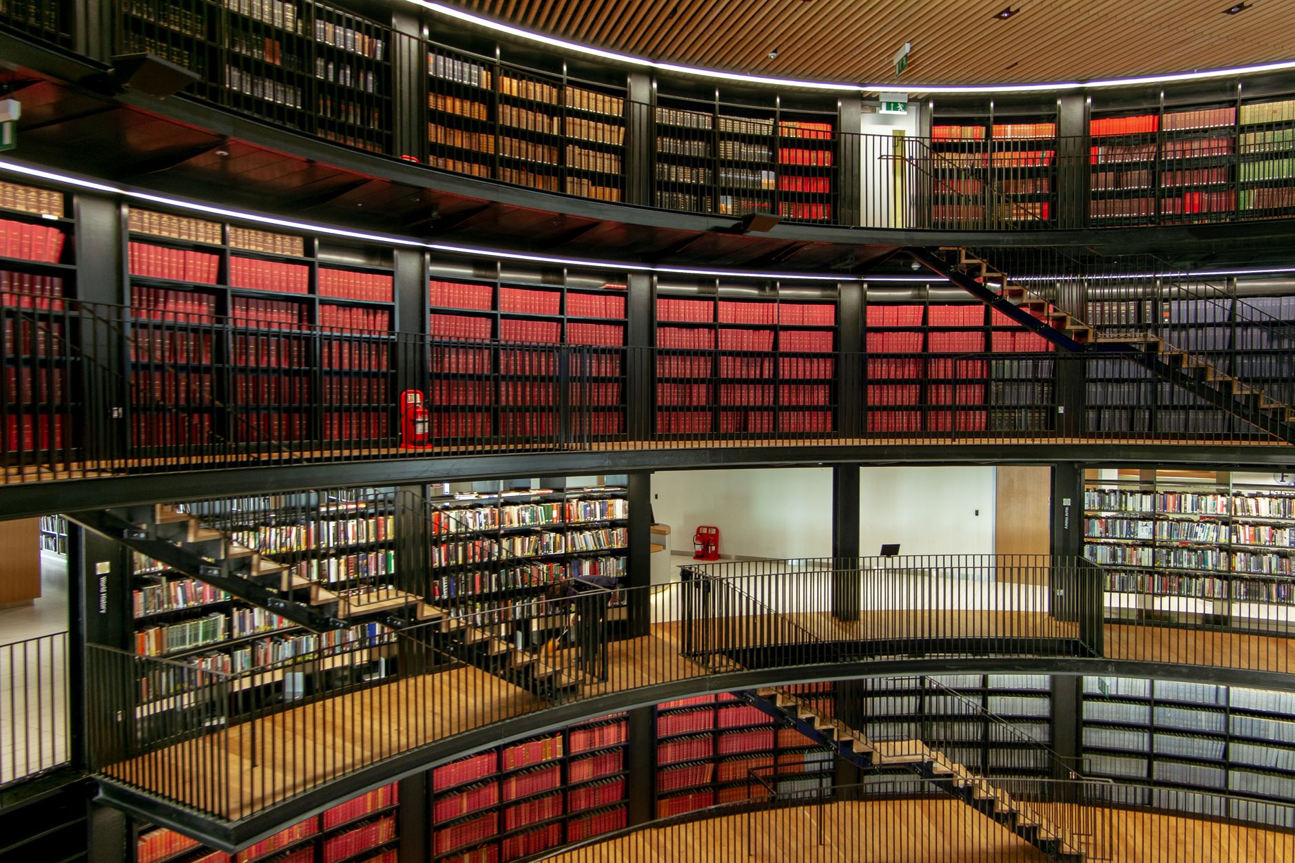 Rows of bookshelves beside metal railings and staircases in a spacious modern public library