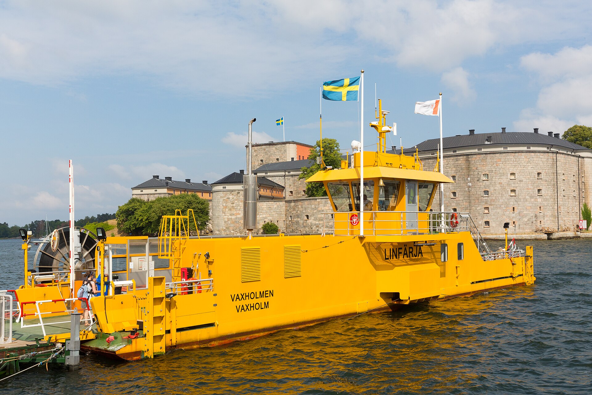 The cable ferry from Vaxholm town at its dock, with Vaxholm Fortress in the background