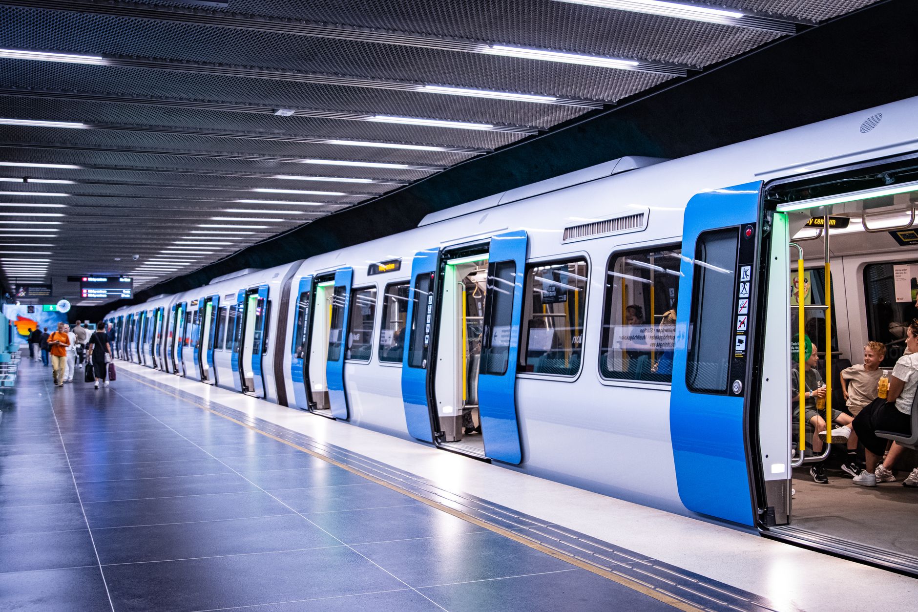 Stockholm metro platform with passengers boarding train. Urban transportation scene.